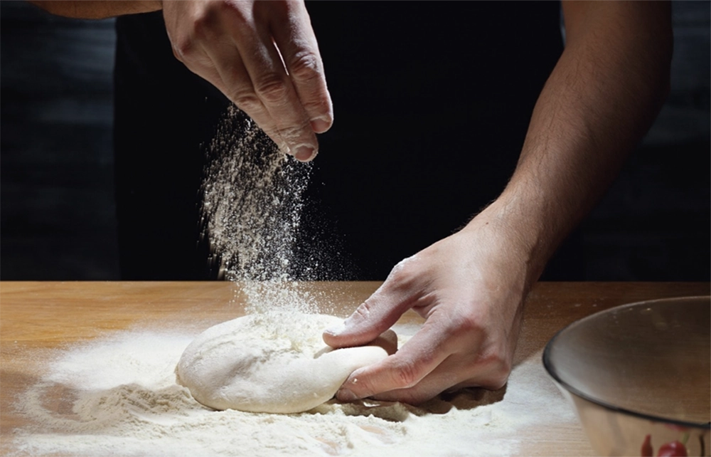 Rolling out dough for a pizza pie crust.